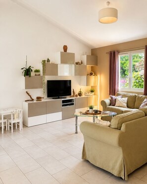 Ein modernes Wohnzimmer mit Flachbildfernseher, einer Couch, einem Couchtisch und einem TV-Schrank mit Regalen.