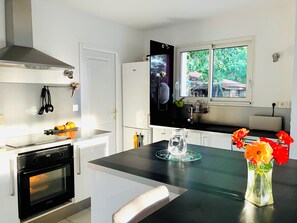 Eine moderne Küche mit Einbauofen, Kühlschrank und einem Fenster mit Blick auf Grünfläche.