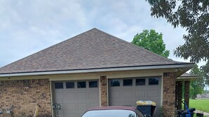 Een rode Corvette geparkeerd voor een huis met een garage.