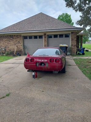 Ein roter Corvette parkt vor einem Haus mit Garage.