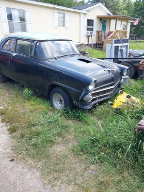 Ein Oldtimer auf einer Wiese, im Hintergrund ein Haus.