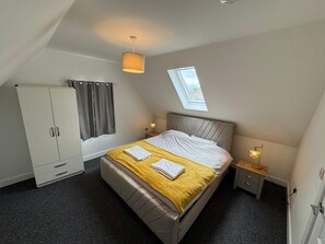 A bedroom with a bed, a wardrobe, a window, and a skylight.