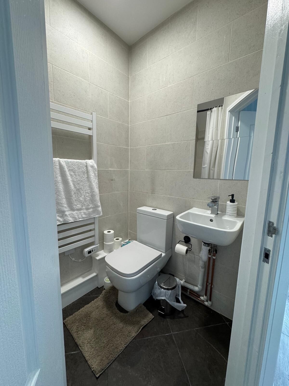 A compact bathroom with a toilet, sink, and towel rack.