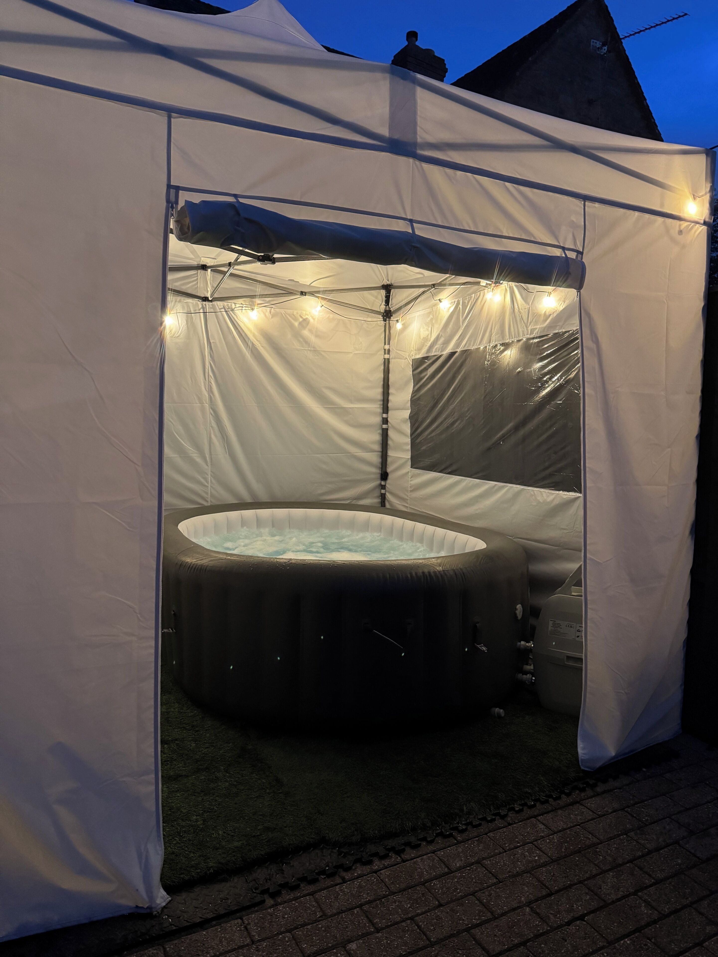 Una carpa con jacuzzi en su interior, rodeada de luces de cadena.