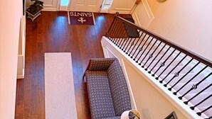A view of a hallway with a staircase, a bench, a rug, a door, and a chandelier. - Welcome to Mr. T's Palace!
Stay big. Relax easy. 
Your Home away from Home. (Jonesboro)