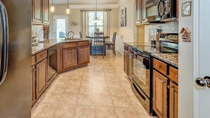 A kitchen with wooden cabinets, a central island, and a dining area with a table and chairs. - Welcome to Mr. T's Palace!
Stay big. Relax easy. 
Your Home away from Home. (Jonesboro)