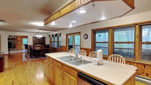 A kitchen with wooden cabinets, a dishwasher, a sink, and a dining area with chairs.