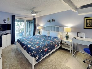 A bedroom with a bed, a desk, a chair, a ceiling fan, and a TV. - Lakeview Retreat (Oakland)
