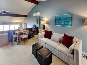 A cozy living room with a sofa, a desk, and a chair. There is a painting on the wall and a ceiling fan. - Lakeview Retreat (Oakland)