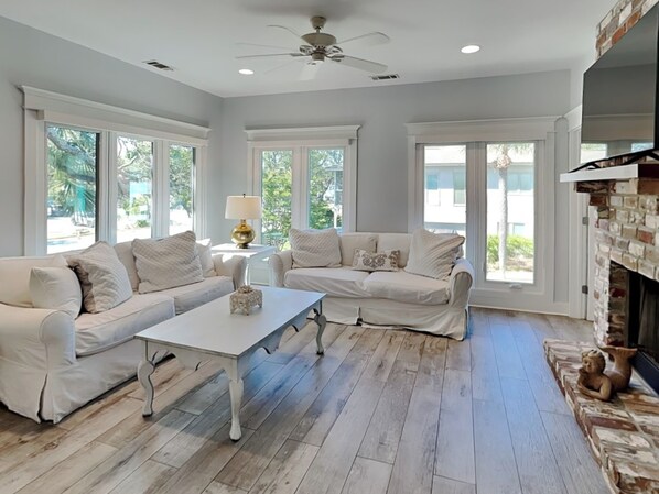 A spacious living room with a white sofa set, a coffee table, and a fireplace. - Tybee Straits 17 (Tybee Island)