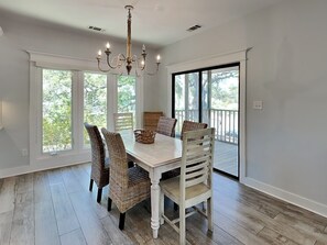 A dining room with a white table, wicker chairs, and a chandelier. - Tybee Straits 17 (Tybee Island)