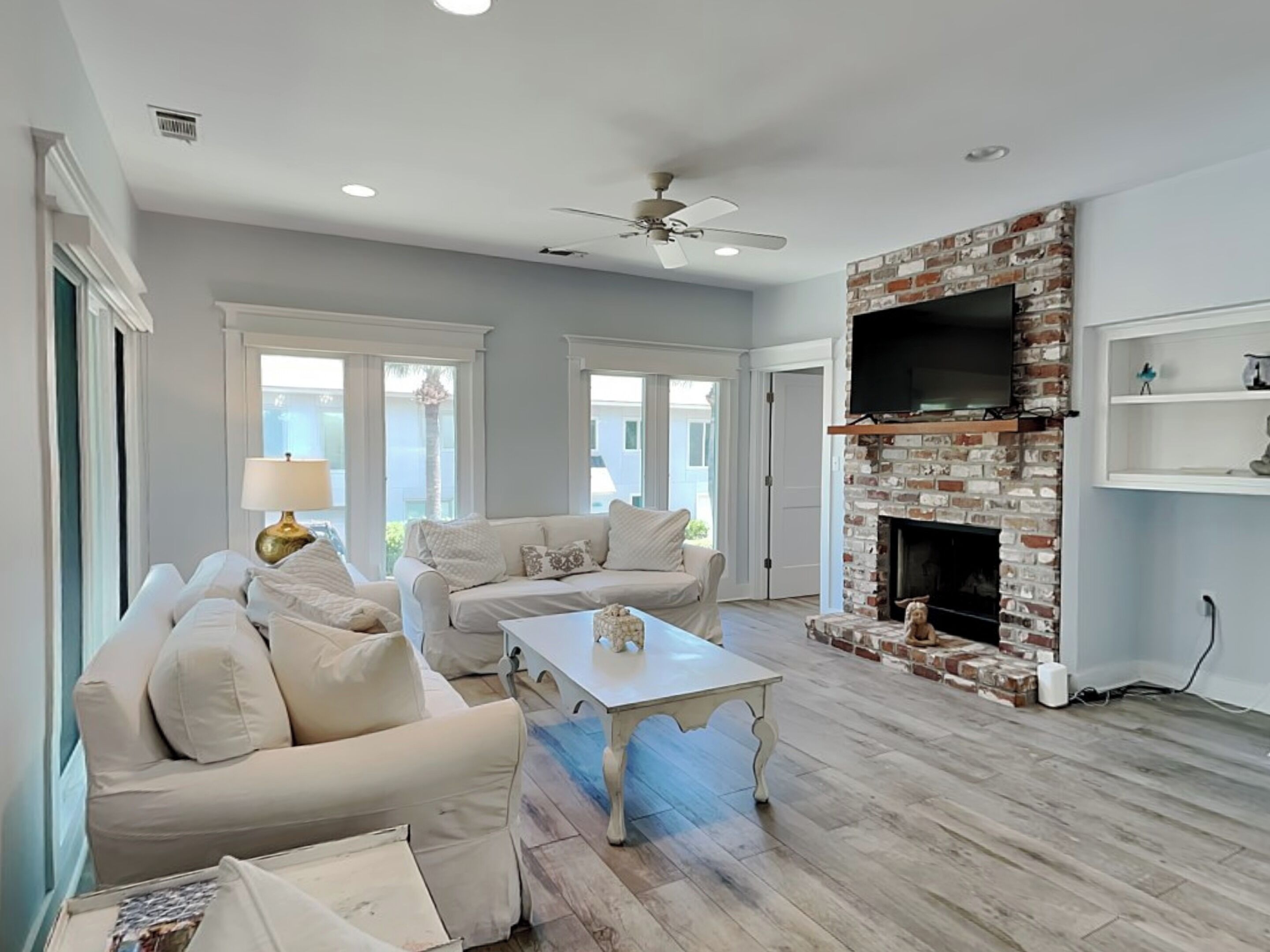 A living room with a fireplace, two sofas, a coffee table, and a TV mounted on a brick wall.