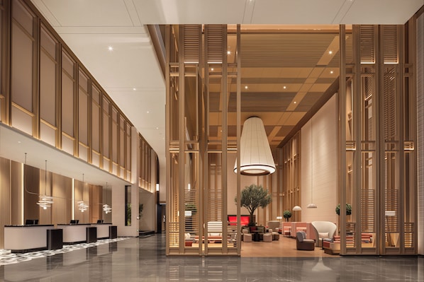 A modern hotel lobby with a reception desk, seating area, and decorative wooden panels.