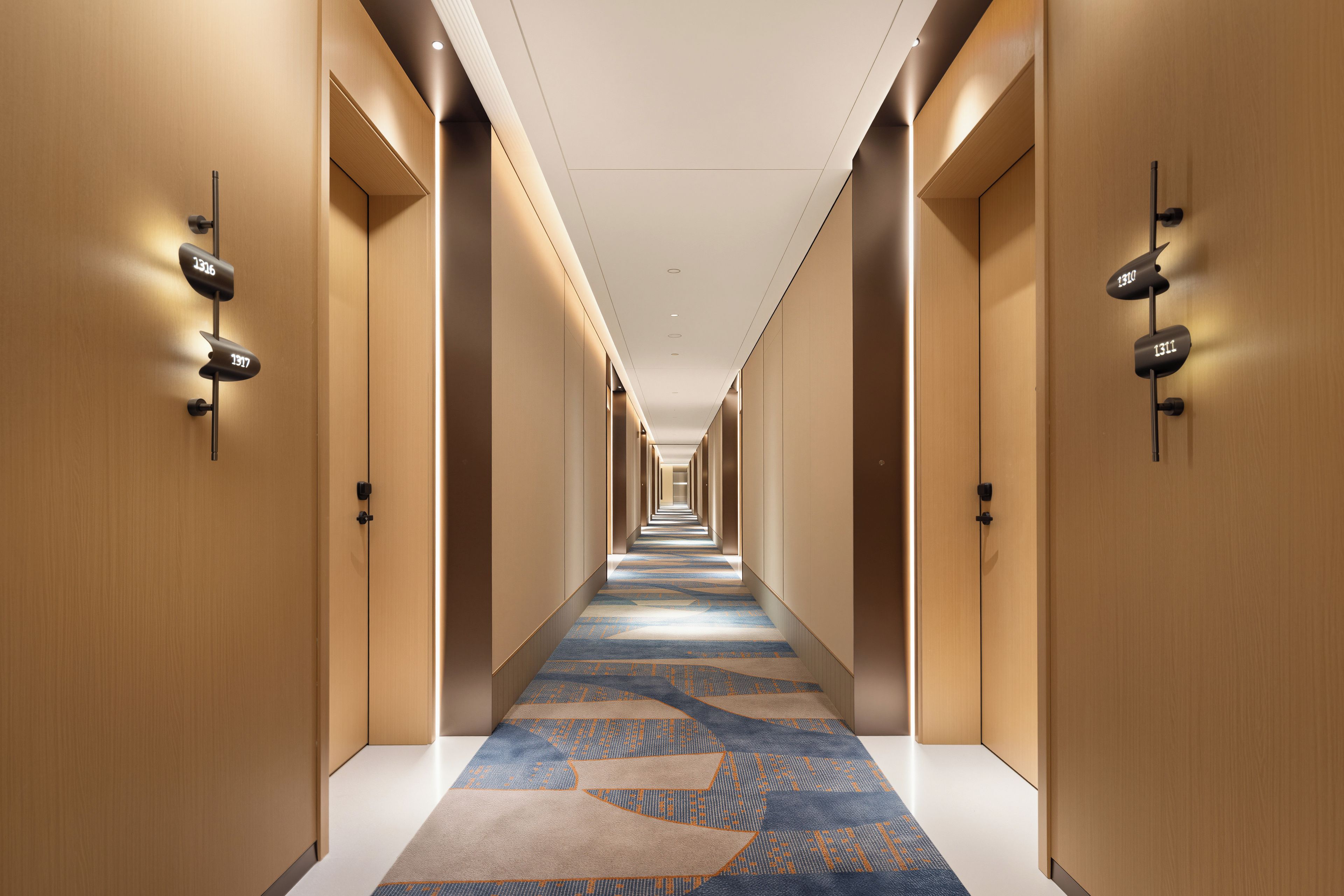 Un pasillo de hotel con suelo alfombrado, paredes de madera y puertas numeradas.