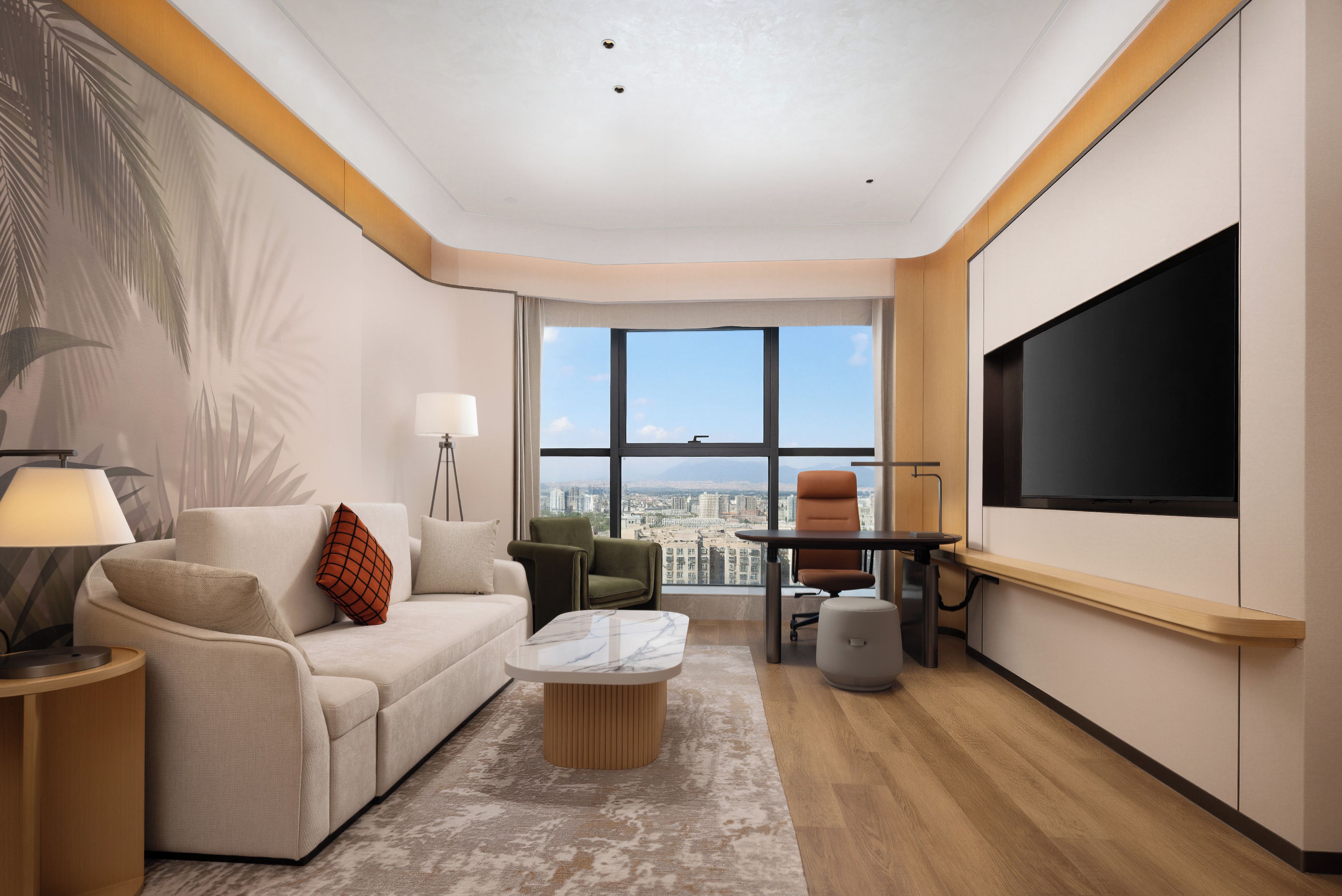 A modern living room with a sofa, armchairs, a coffee table, and a TV.