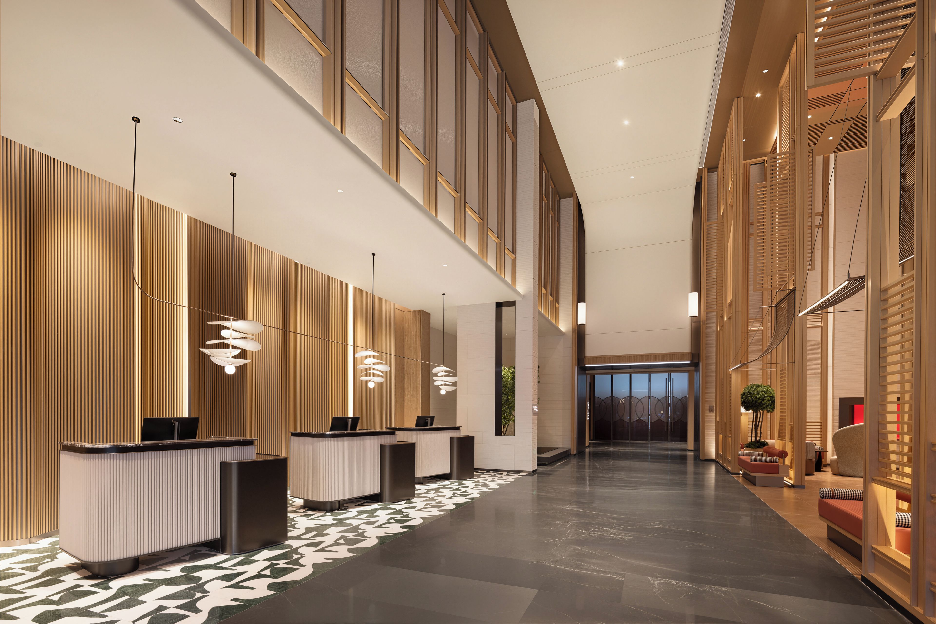 Un moderno hall de hotel con recepción, zona de estar y un amplio ventanal.