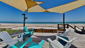 Un terrazzo in legno con sedie e un tavolo, con vista sulla spiaggia.