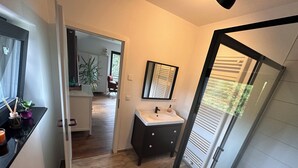 A modern bathroom with a sink, mirror, and a view of the outdoors through a glass door. - Haus an der Panke, room with bathroom (Panketal)