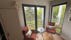 A balcony with wicker chairs, a small round table, and a white door. - Haus an der Panke, room with bathroom (Panketal)