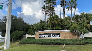 A sign for Hampton Lakes with a stone wall and palm trees. - Lakeview Villa (Davenport)