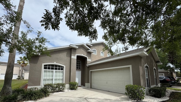 A residential house with a garage, a driveway, and a well-maintained lawn. - Lakeview Villa (Davenport)