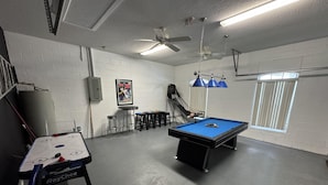 A recreational room with a pool table, a shuffleboard table, and a ceiling fan. - Lakeview Villa (Davenport)