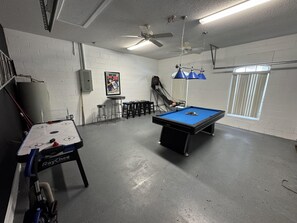 Ein Freizeitraum mit Billardtisch, Shuffleboard und Deckenventilator.