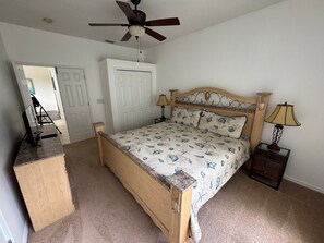 Ein Schlafzimmer mit einem hölzernen Bett, zwei Nachttischlampen, einem Deckenventilator und einem Schreibtisch mit Stuhl.