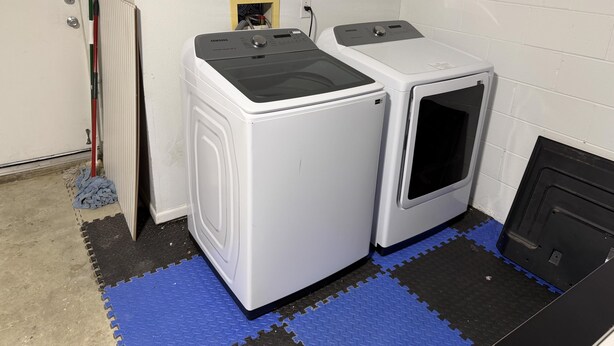 A laundry room with two white washing machines, a mop, and a door. - Beach Bums Villa (Davenport)