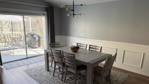 A dining area with a marble table, wooden chairs, and a chandelier. - Beach Bums Villa (Davenport)