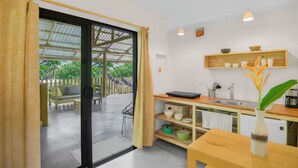 A modern kitchen with a dining area, a hammock, and a view of the outdoors. - Jungle Studio -Steps to Beach-Wi Fi -AC-Work-Surf (Santa Teresa)
