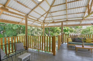 A covered outdoor area with a wooden deck, a sofa, and a small table. - Jungle Studio -Steps to Beach-Wi Fi -AC-Work-Surf (Santa Teresa)