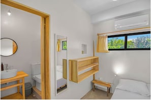 A modern bathroom with a wooden vanity, a toilet, a mirror, and a window with a view of greenery. - Jungle Studio -Steps to Beach-Wi Fi -AC-Work-Surf (Santa Teresa)