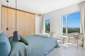 Un dormitorio con cama, una silla, una mesa y vistas al paisaje.