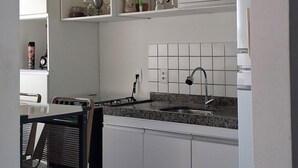 Ett kök med vita skåp, en bänkskiva i granit, ett handfat och en stol.
