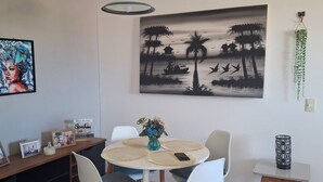 En matplats med ett bord, stolar, en vas med blommor, en inramad tavla och en målning som hänger på väggen.