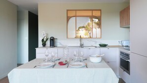 Una cocina moderna con una mesa de comedor para cuatro personas, una cafetera y un ventanal con vistas.