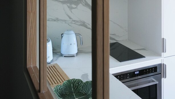 Una cocina moderna con encimera de mármol, armarios de madera y horno integrado.