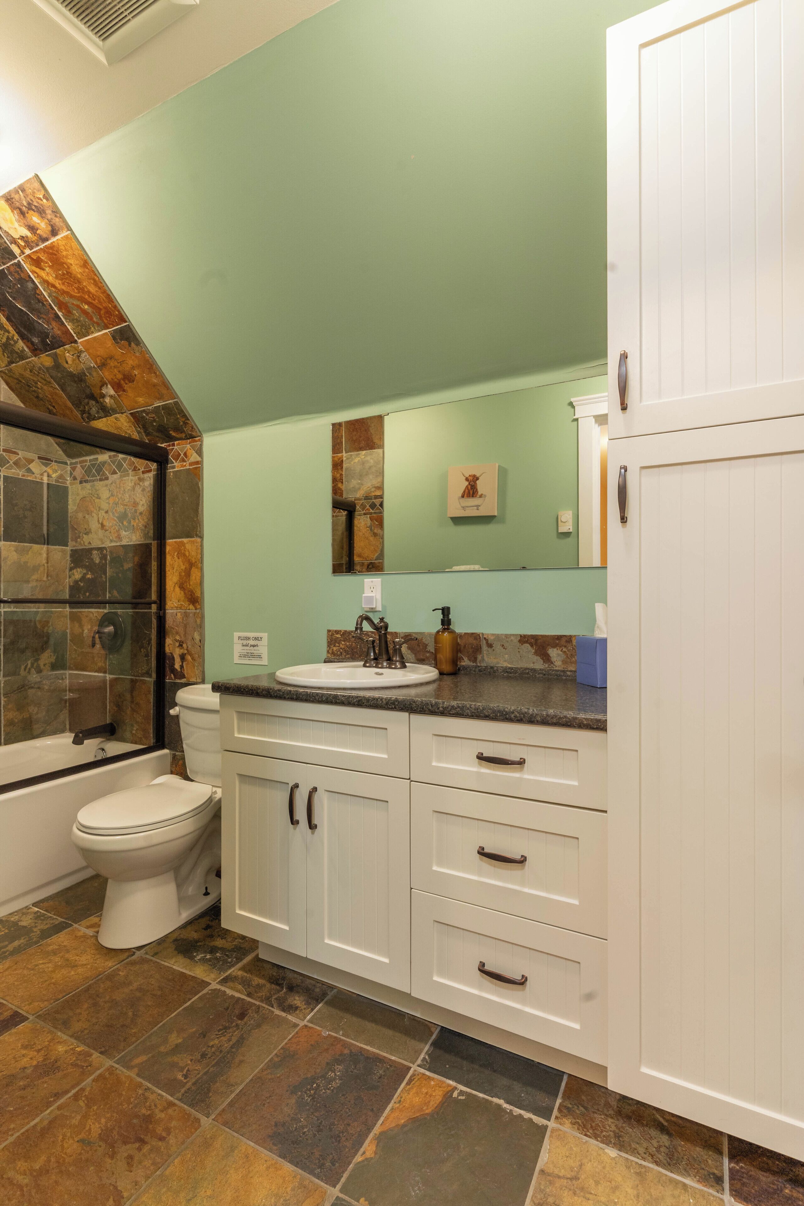 A bathroom with a toilet, sink, and shower area.