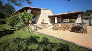 A house with a stone facade, a covered patio, and a gravel driveway. - 3-bedroom family house, swimming pool, garden and terrace near Uzès (Serviers-et-Labaume)