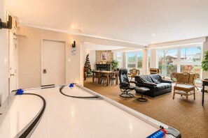 A spacious living area with a billiards table, a fireplace, and a dining area with a Christmas tree.
