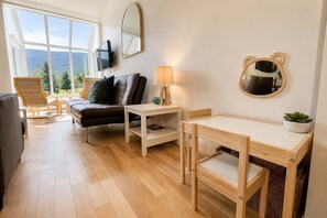 A cozy living room with a sofa, a small table, a TV, and a bear-shaped mirror.
