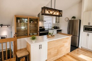 A modern kitchen with a central island, wooden cabinetry, and a built-in microwave.