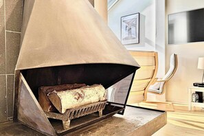 A fireplace with a metal grate, a log, and a protective cover.