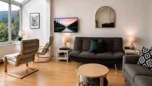 A modern living room with a sofa, armchairs, a coffee table, and a TV.