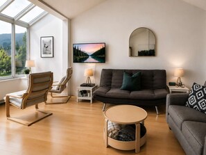 A modern living room with a sofa, armchairs, a coffee table, and a TV.