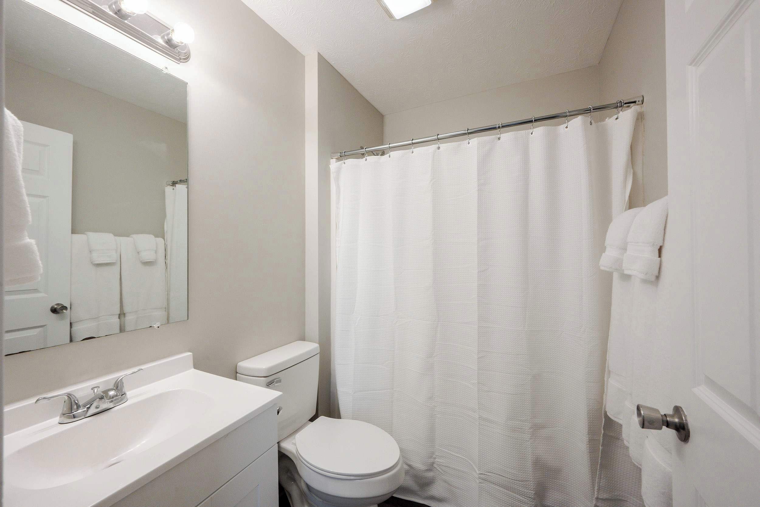 A bathroom with a white sink, toilet, and shower curtain.