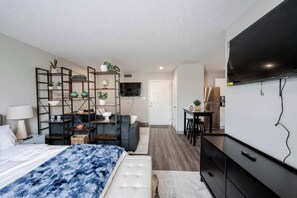 Ein modernes Schlafzimmer mit Bett, Fernseher, Schreibtisch und Regalelement.