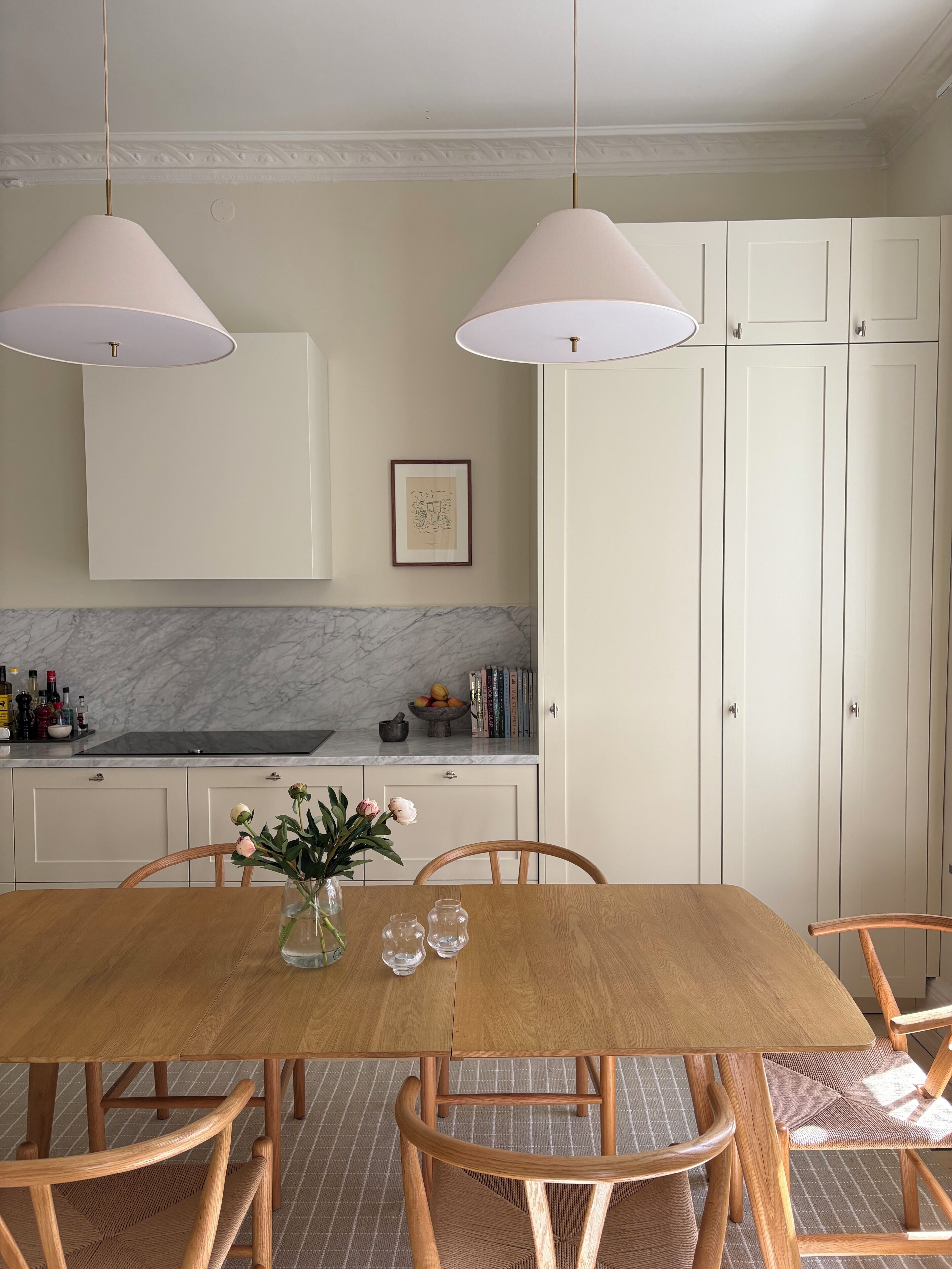 A dining area with a wooden table, chairs, and pendant lights.