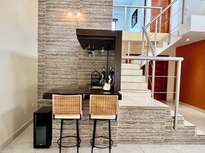 A bar area with two wicker chairs, a dark countertop, and a speaker. - Spacious Caribbean Home in Downtown Cozumel | Perfect for Groups (Cozumel)